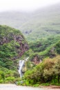 Waterfall in Ayn Khor and Lush green landscape, trees and foggy mountains at tourist resort, Salalah, Oman