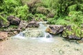 Waterfall in Ayn Khor and Lush green landscape, trees and foggy mountains at tourist resort, Salalah, Oman Royalty Free Stock Photo