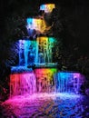A waterfall cascade lit with bright colours at night