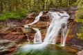 A waterfall cascading over layers of multi-colored rocks in Glacier National Park, Montana Royalty Free Stock Photo