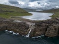 Waterfall and Cliffs of Traelanipa with the lake above the ocean, Faroe Islands, Denmark, Europe, aerial view Royalty Free Stock Photo