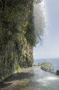 Waterfall on closed old road on the edge of rocky cliff between Ponta do Sol and Jardim do Mar, Madeira island, Portugal Royalty Free Stock Photo