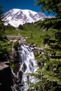 Waterfall crashes down in front of the snow capped Mount Rainier Royalty Free Stock Photo