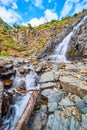 Waterfall down angled slope of gray rocks in the mountains