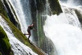 waterfall extreme brave man as superhero running jump and dive from the rock into the wild river water.