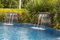 Waterfall falling in a blue lagoon swimming pool in hotel. Royalty Free Stock Photo