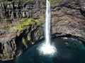 Waterfall falling from the cliff into the sea, aerial drone view, Faroe islands
