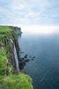 Waterfall falling from high cliffs into the ocean.