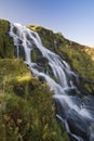 Waterfall flowing down hill with blue sky
