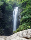 A waterfall is flowing down a rocky cliff Royalty Free Stock Photo