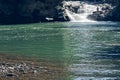 A waterfall flowing down from a Sheer cliffs . Blue clear water of mountain the river. Rocky stones and forest Alpine landscape Royalty Free Stock Photo