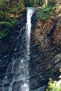 A waterfall flowing down from a Sheer cliffs . Blue clear water of mountain the river. Rocky stones and forest Alpine Royalty Free Stock Photo