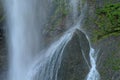 Waterfall flowing over aged and mossy grey rock