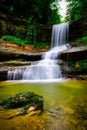 waterfall flowing over a rocky cliff into a small pool of water Royalty Free Stock Photo