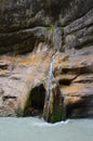 The waterfall flows down a thin stream over a rock and falls into a mountain river Royalty Free Stock Photo