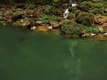 The waterfall flows into the green lake