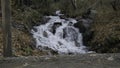 Waterfall flows over the rocks to the river. Creative. Man hiker walking in front of cold mountainous stream in autumn Royalty Free Stock Photo