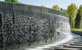 Waterfall flows in streams into granite bed of artificial river. Fountain in form of huge bowl. Public landscape city park Krasnod