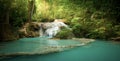 Waterfall in forest with sunlight beams and rays through trees Royalty Free Stock Photo