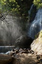 Waterfall and lower cascade in the forest with water fog lit wit Royalty Free Stock Photo