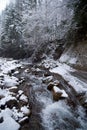 Waterfall in the mountain winter forest with snow-covered trees and snowfall Royalty Free Stock Photo