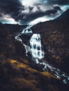 Waterfall in Norway with yellow/gold grading and dramatic clouds