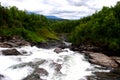 Waterfall in the Norwegian river valley in the forest against the backdrop of mountains Royalty Free Stock Photo