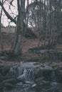 waterfall over the rocks in river stream in forest in late autumn with naked trees and grey colors in nature - vintage old film Royalty Free Stock Photo
