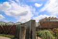 A waterfall over a stone wall with a doorway on a curved footpath in the garden with blue sky and powerful clouds