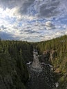 Waterfall Between Pine Trees with Cloudy Blue Sky