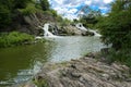 The waterfall on the river flows through and over the rocks cove Royalty Free Stock Photo