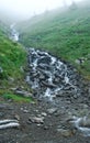 Waterfall on rocks, mist and green mountain slopes, nobody