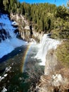 Waterfall with snow and rainbow in the mist Royalty Free Stock Photo