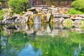 Reflection of greenery in the water of a decorative waterfall in a summer garden. Landscape design Royalty Free Stock Photo