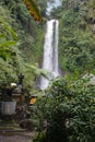 Waterfall with stone shrines and greenery in Bali countryside, Indonesia