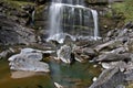 Waterfall surrounded by rocks covered in mosses under the sunlight - perfect for wallpapers Royalty Free Stock Photo