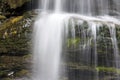 Waterfall surrounded by rocks covered in mosses under the sunlight - perfect for wallpapers Royalty Free Stock Photo