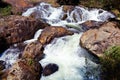 Waterfall with swift current between rocky stones