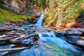 Waterfall tucked into canyon with vibrant blue water and river rocks Royalty Free Stock Photo