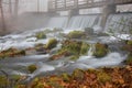 Waterfall under a bridge on a foggy fall morning.