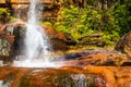 Waterfall white streams falling from mountain top at yellow rocks with rainbow at morning Royalty Free Stock Photo