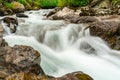 a waterfall in the wilderness with large rocks and trees surrounding Royalty Free Stock Photo