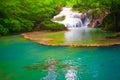 Waterfalls and fish swim in the emerald blue water in Erawan National Park. Erawan Waterfall is a beautiful natural rock waterfall Royalty Free Stock Photo