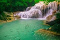 Waterfalls and fish swim in the emerald blue water in Erawan National Park. Erawan Waterfall is a beautiful natural rock waterfall Royalty Free Stock Photo