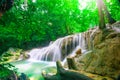 Waterfalls and fish swim in the emerald blue water in Erawan National Park. Erawan Waterfall is a beautiful natural rock waterfall Royalty Free Stock Photo