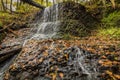 Waterfall over lush greens and golden fall foliage Royalty Free Stock Photo
