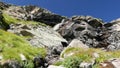 Waterfalls flowing in idyllic uncontaminated environment crossing green meadows and boulders on the Alps in summer. Slow motion, z