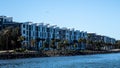 Waterfront apartment condominiums in suburban community on riverbank with tree lined walkway, blue sky in background