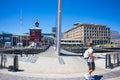 Waterfront bridge that leads to the Silo District. People in face masks walking past and over it. Colorful architecture in backgro