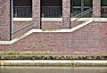 Waterfront building with sidewalk, flight of stairs, brick wall and brick pillars